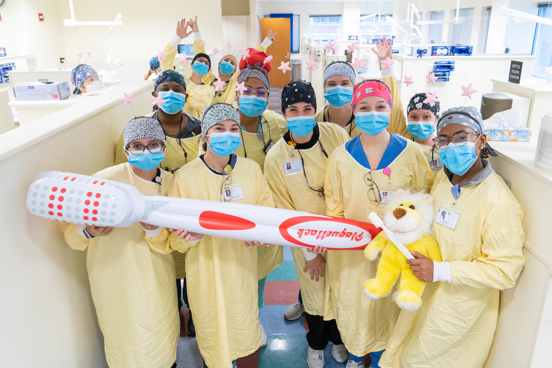 Dental students holding giant toothbrush during give kids a smile day