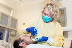 Blonde woman in mask using dental tools on a patient. 